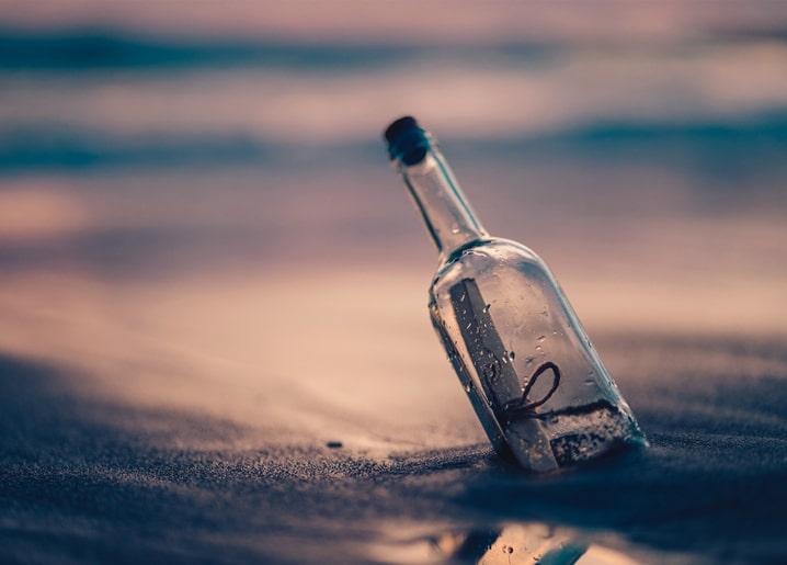 Verkorkte Flaschenpost im Sand am Strand bei Dämmerung