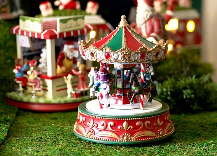 Bemaltes Miniatur-Karussell mit Pferden vor Santas beleuchteter Werkstatt
