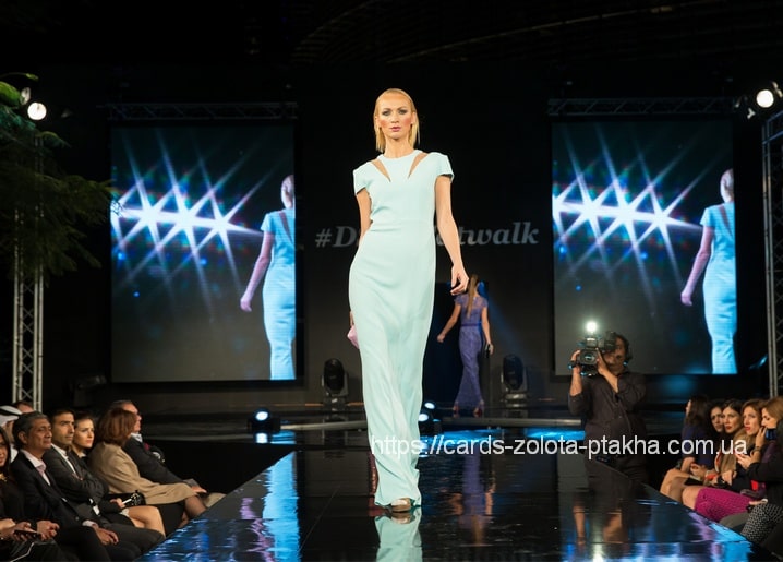 Model in mintfarbenem Kleid auf dem Laufsteg vor sternförmigen LED-Screens
