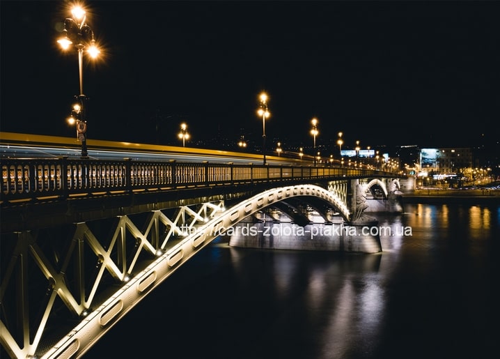 Beleuchtete stählerne Bogenbrücke bei Nacht mit verwischten Lichtspuren vorbeifahrender Fahrzeuge