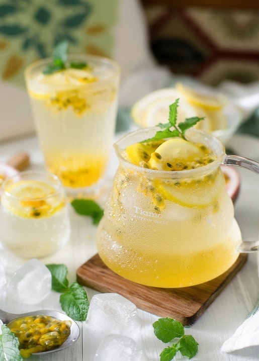 Krug und Gläser mit Passionsfrucht-Limonade, Minze, Eis und Zitronenscheiben