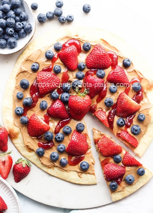 Dessert-Pizza mit Erdnussbutter, Erdbeeren und Blaubeeren, in Stücke geschnitten