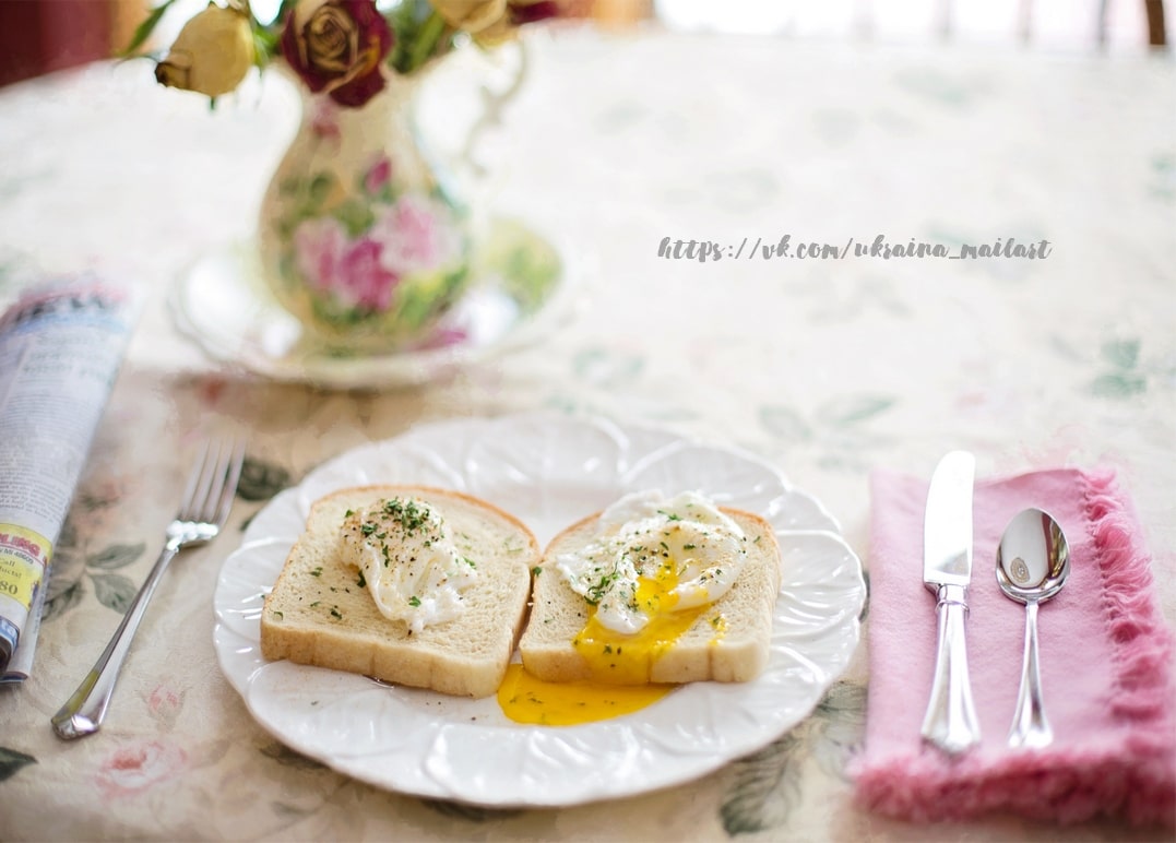 Pochierte Eier auf Toast mit rosa Serviette, verblühten Rosen und Zeitung