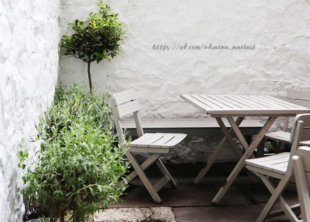 Getopftes Formgehölz und Lavendel neben einem Klapptisch in einem weißen Innenhof
