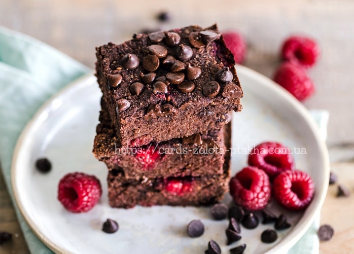 Gestapelter Schoko-Himbeer-Brownie mit Schokostreuseln auf weißem Teller