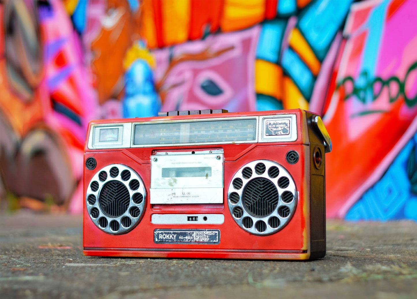 Roter Vintage-Kassettenrekorder vor einer bunten Graffiti-Wand
