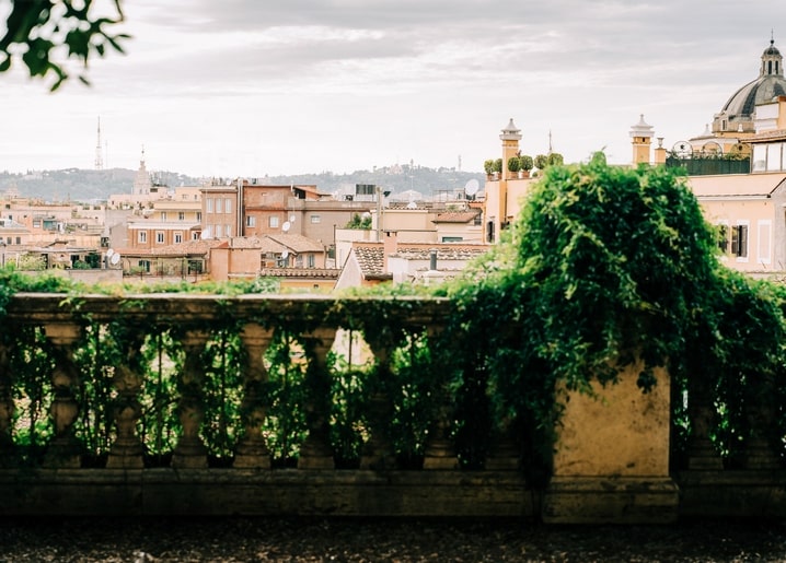 Вид на черепичні дахи та купол крізь кам'яну балюстраду, обвиту плющем