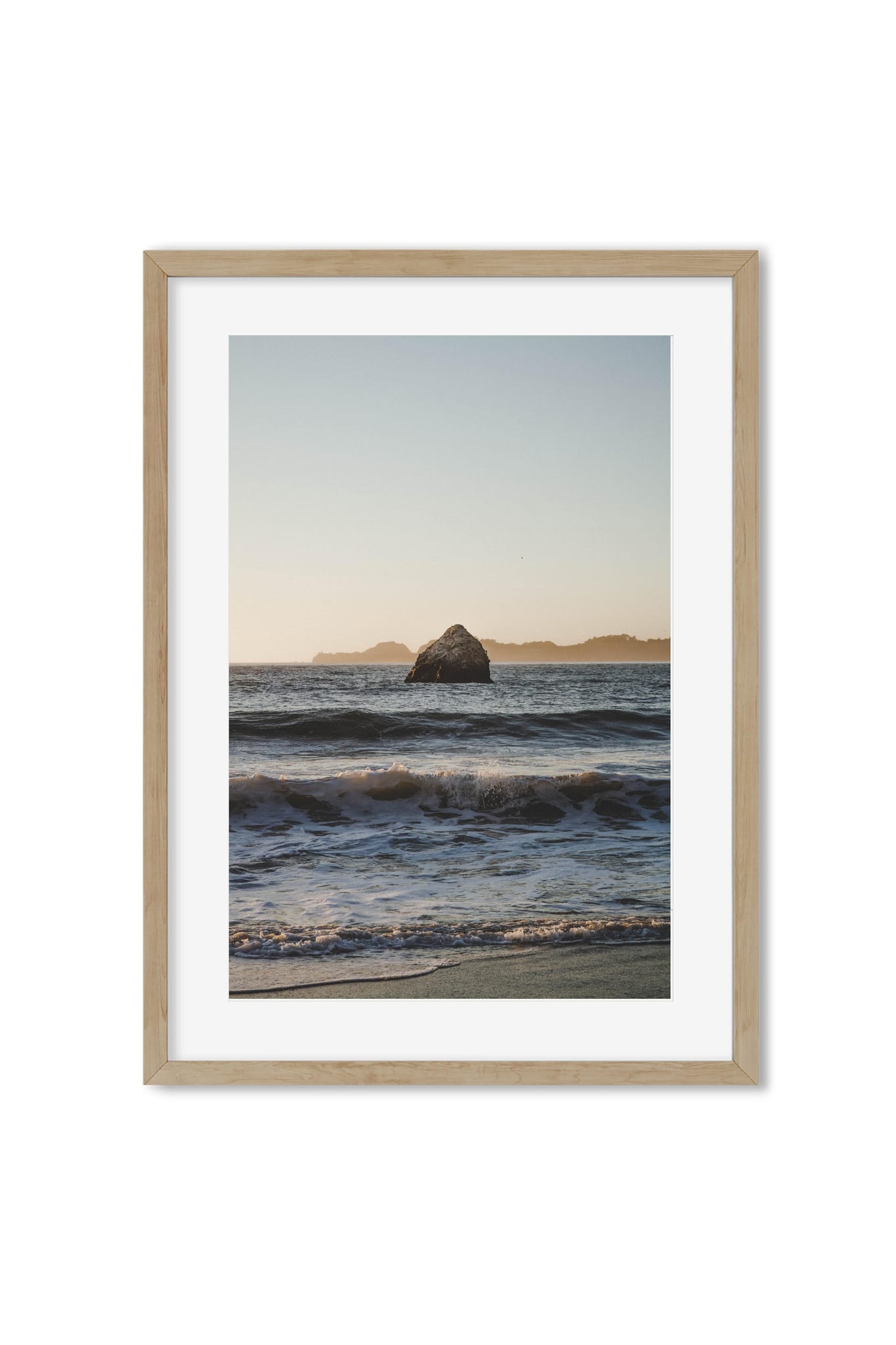 Framed poster of a sea stack rock in ocean waves at golden-hour sunset