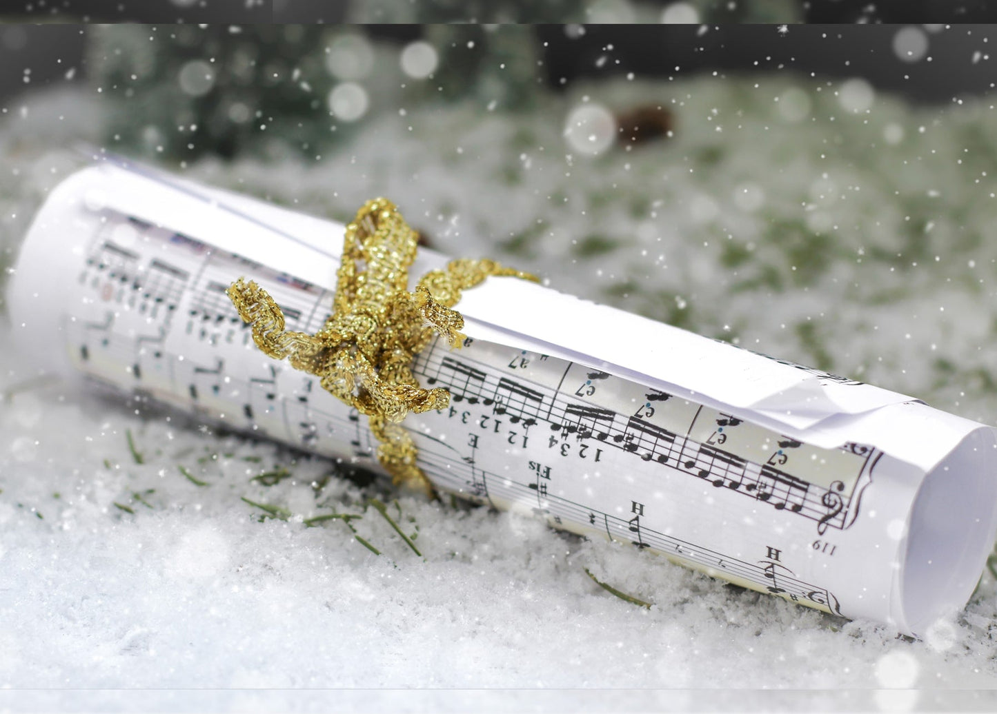 Notenblatt mit goldener Schleife liegt im Schnee mit Schneeflocken