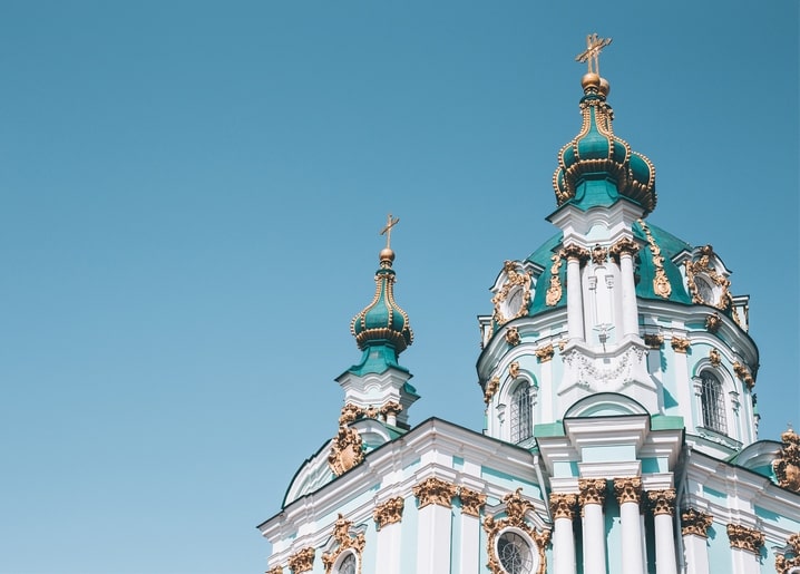 Бірюзові бані з позолотою Андріївської церкви на тлі синього неба в Києві