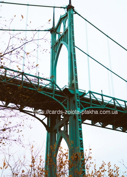 Teal Gothic tower of the St. Johns Bridge in Portland framed by bare autumn branches