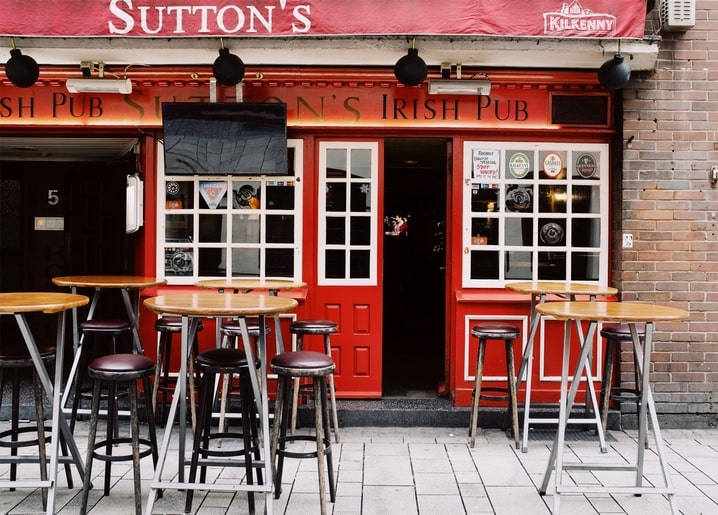 Порожні столики та стільці біля червоного фасаду ірландського пабу Sutton's