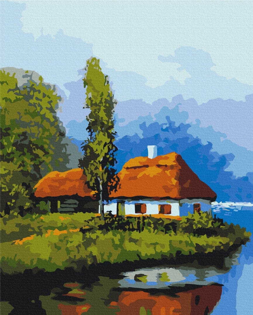 Weiß getünchtes Reetdachhaus am ruhigen See, gespiegelt im Wasser unter einem hohen Baum.