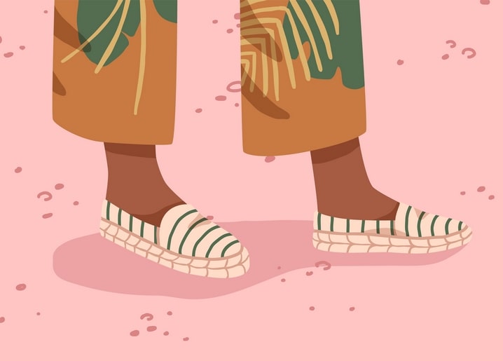 Cropped legs in tropical-leaf print trousers and striped espadrilles on a pink background