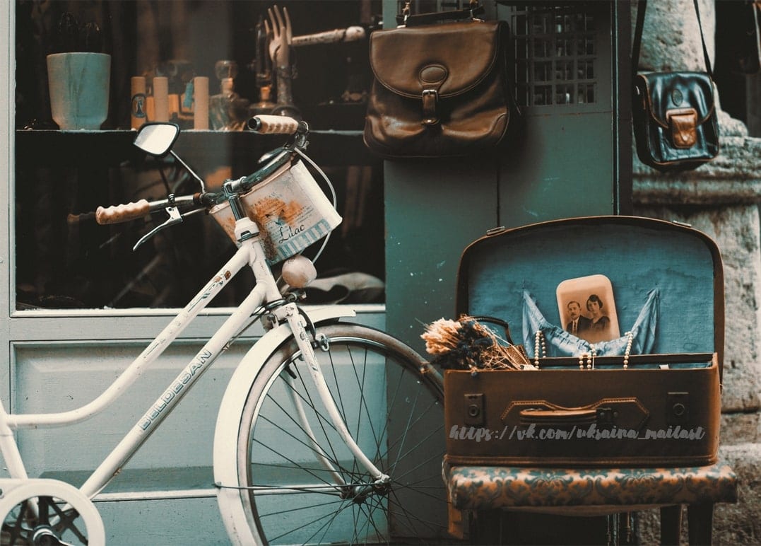 Vintage-Fahrrad und offener Koffer mit altem Foto vor türkisfarbener Ladenfront
