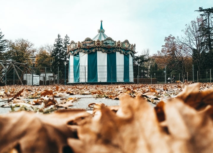 Смугаста вінтажна каруселька серед опалого осіннього листя в парку