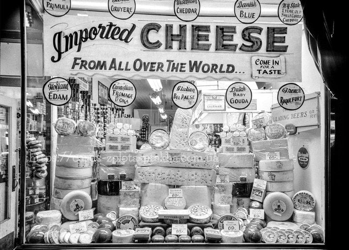 Vintage shop window filled with wheels of imported cheese from around the world