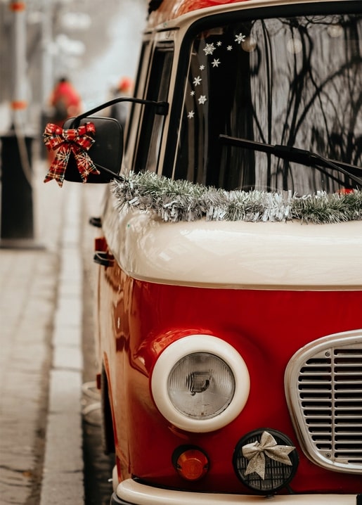 Roter Oldtimer-Bus mit Lametta-Girlande und karierter Schleife geschmückt