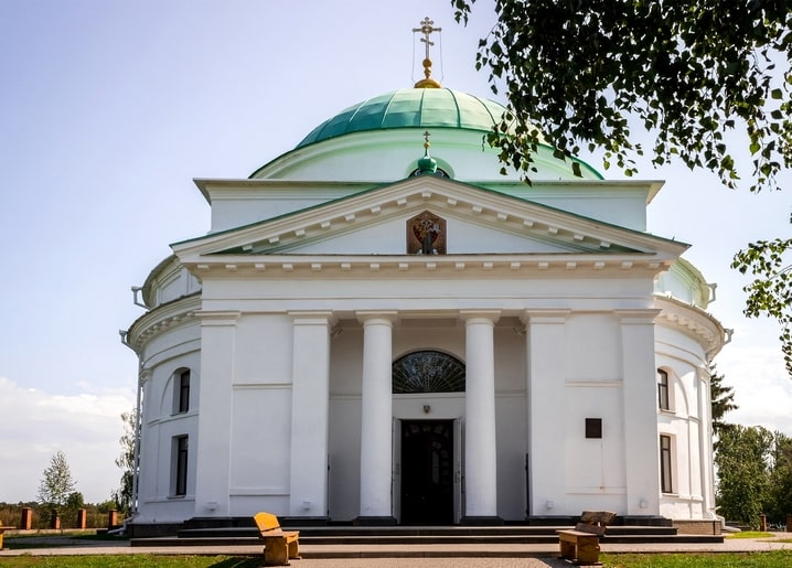 Біла церква в стилі ампір із зеленим куполом і колонадою в Диканці