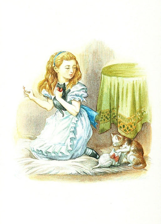 Alice hält ein schwarzes Kätzchen, daneben spielt ein weißes Kätzchen mit einer Schleife