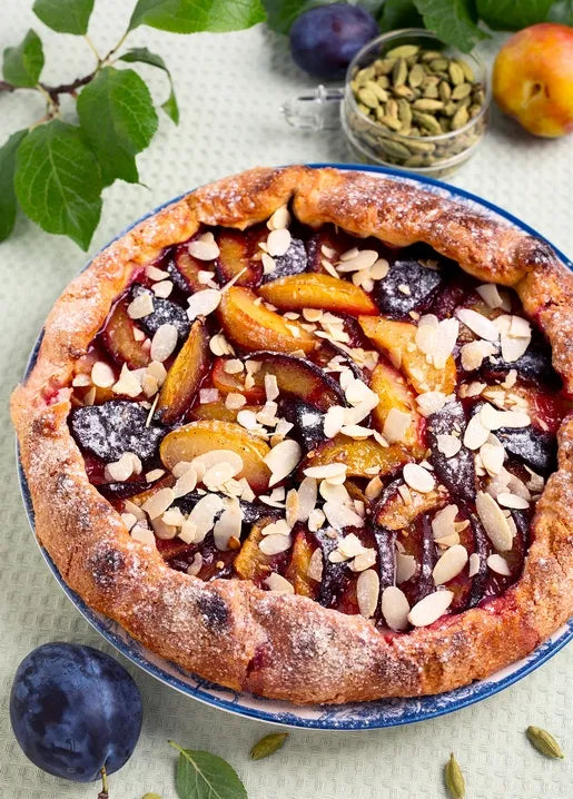 Autumn food postcard featuring a rustic plum and peach galette with almonds and cardamom