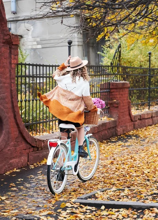 Autumn photo postcard featuring a woman riding a bicycle through a leaf-covered street with flowers