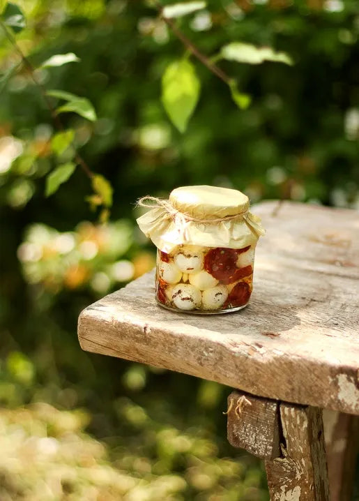 Food postcard featuring a small glass jar of homemade fruit preserve on a rustic wooden table