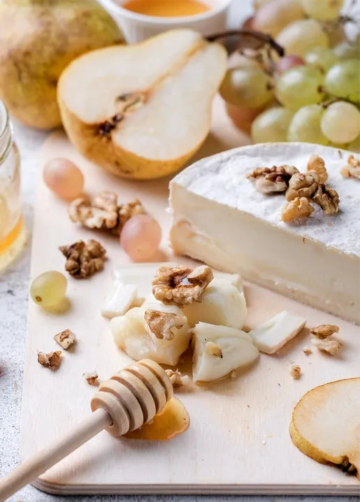 Food postcard featuring pears, soft cheese, green grapes, walnuts and honey on a rustic table