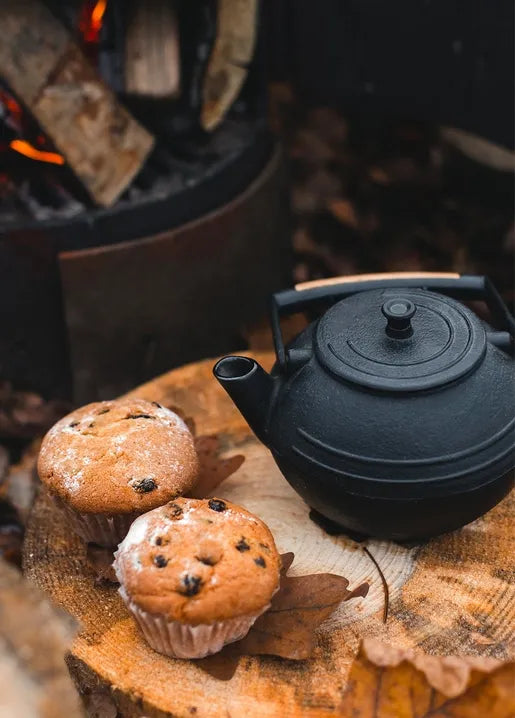 Cozy autumn food postcard featuring a black teapot and two muffins on a rustic wooden table