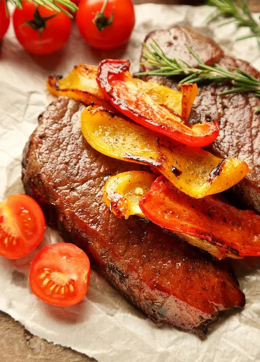 Food postcard featuring grilled steak with roasted red and yellow peppers, tomatoes and rosemary