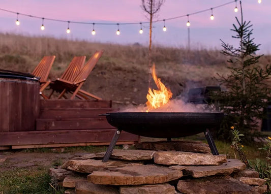 Cozy autumn photo postcard featuring a glowing fire pit, wooden chairs and string lights at dusk