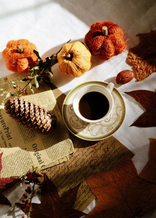 Herbstliches Stillleben mit Kaffeetasse, garnumwickelten Kürbissen, Tannenzapfen und handgeschriebenem Brief