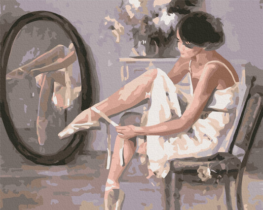 Ballerina im Ankleidezimmer bindet die Bänder ihres Spitzenschuhs vor dem Spiegel