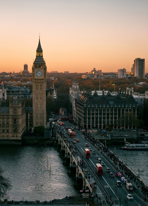 Big Ben clock tower and Westminster Bridge with red buses at golden hour in London