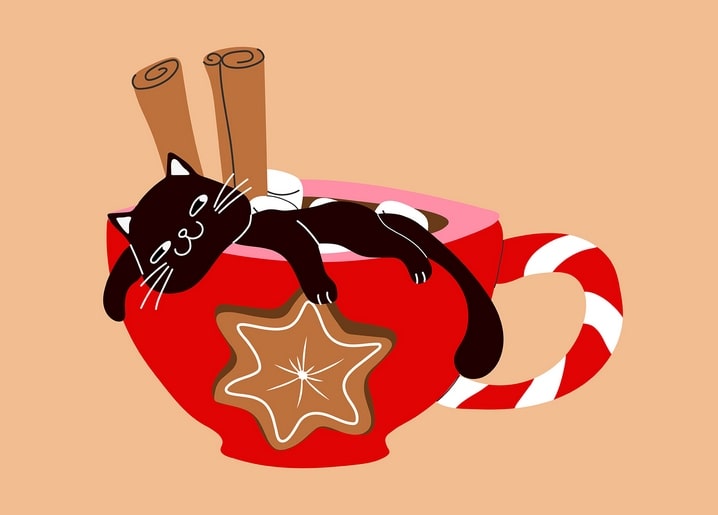 Schwarze Katze liegt in einer Kakaotasse mit Zimtstangen und einer Zuckerstange als Henkel