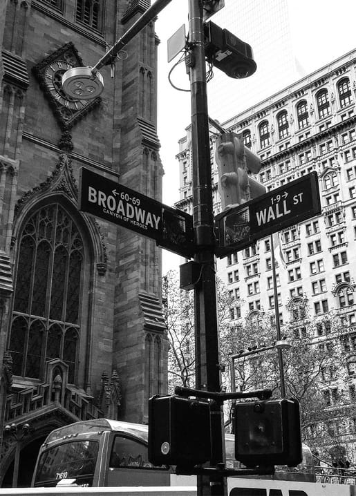 Broadway and Wall Street sign with Trinity Church spire in the background, New York