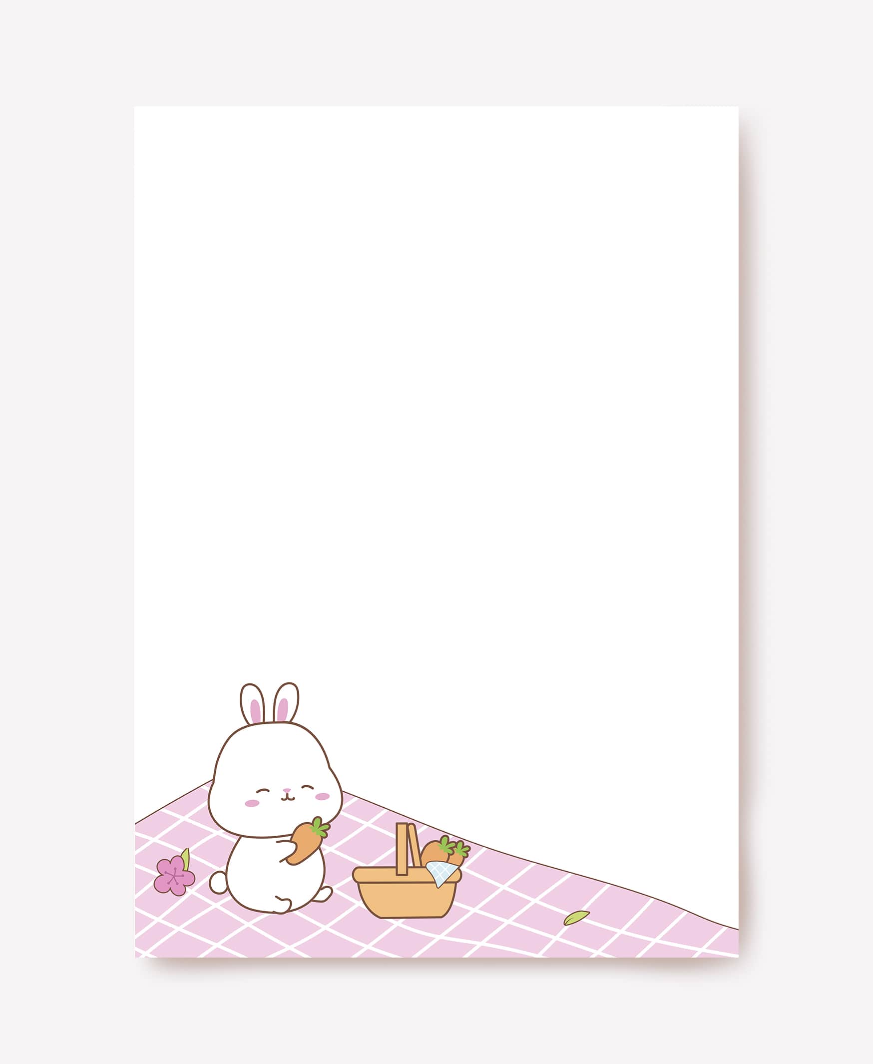 Bunny eating a carrot on a pink picnic blanket beside a woven basket on blank writing paper