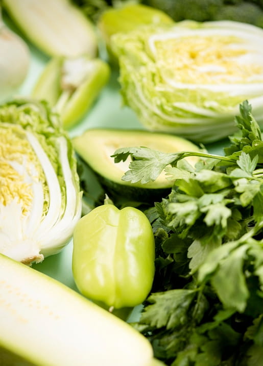 Close-up of halved napa cabbage, zucchini, avocado, green pepper and parsley