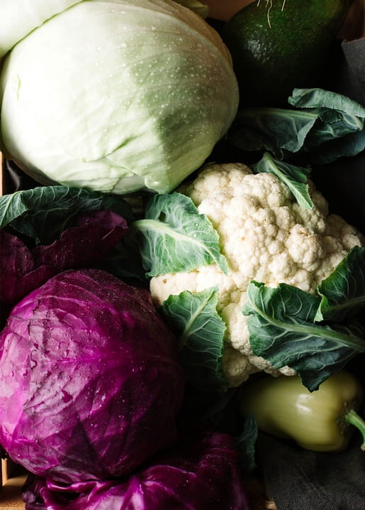 Weißkohl, Rotkohl, Blumenkohl und Paprika dicht gestapelt in einer hölzernen Erntekiste