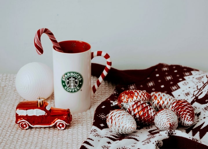 Candy canes, a toy car ornament, and glittered pinecones on a red knitted sweater pattern