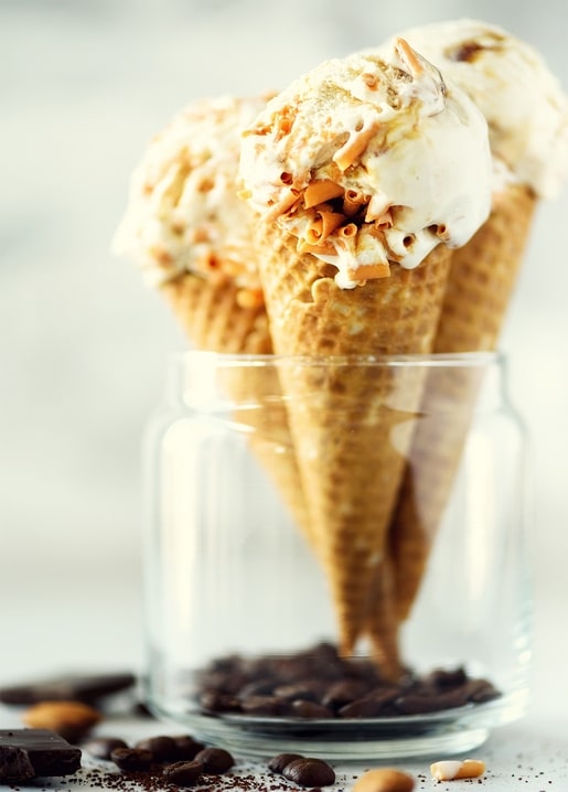 Drei Karamell-Eiswaffeln in einem Glas mit Kaffeebohnen und Schokoladenstückchen