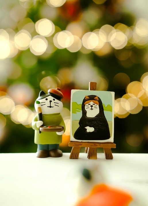 Cat figurine in a painter's beret painting a Mona Lisa with a cat face