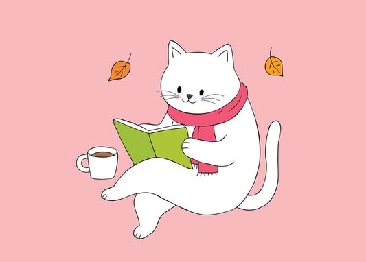 White cat in a scarf reading a book beside a cup of coffee