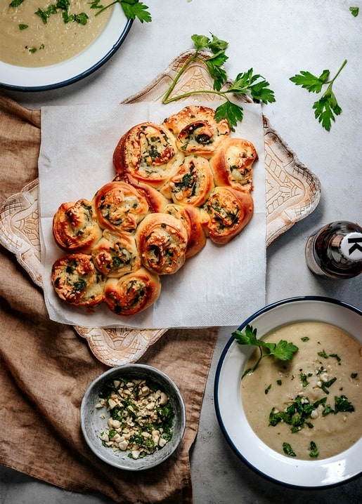 Cheesy herb pull-apart rolls served with bowls of hummus and fresh parsley