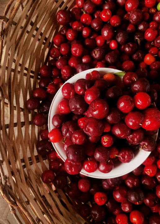 Overhead view of a bowl of cherries inside a large woven basket