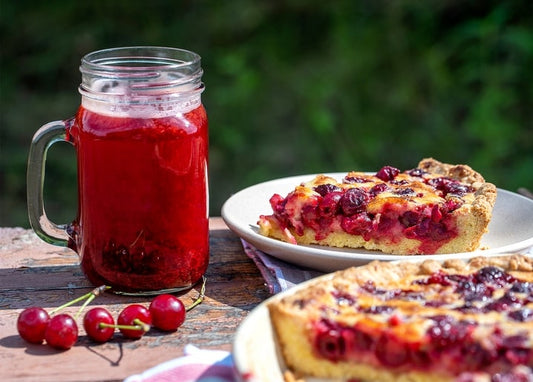 Cherry pie slices beside a jar of cherry juice and fresh cherries