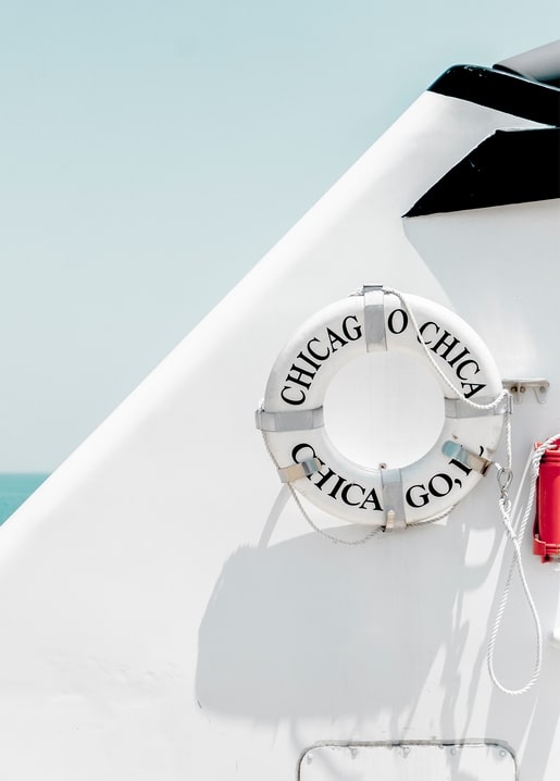 White lifebuoy labeled 'Chicago' mounted on the bow of a white boat at sea