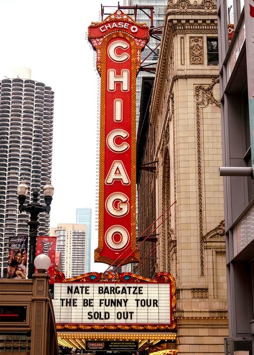 Red neon Chicago Theatre marquee sign against the city skyline at dusk