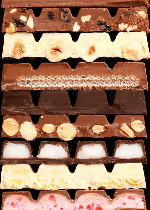 Aufgeschnittene Schokoladentafeln mit Nüssen, Kokos, Waffel und Beerencreme