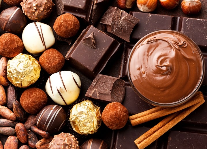 Chocolate truffles, cocoa beans, cinnamon sticks and melted chocolate in a bowl